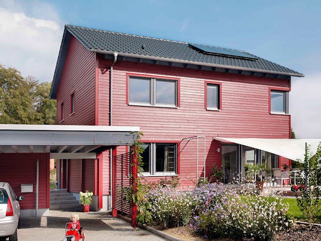 Einfamilienhaus E 20-148.6 des Herstellers SchwörerHaus mit roter Fassade und Satteldach — Fertighausmodell mit rund 137 m²